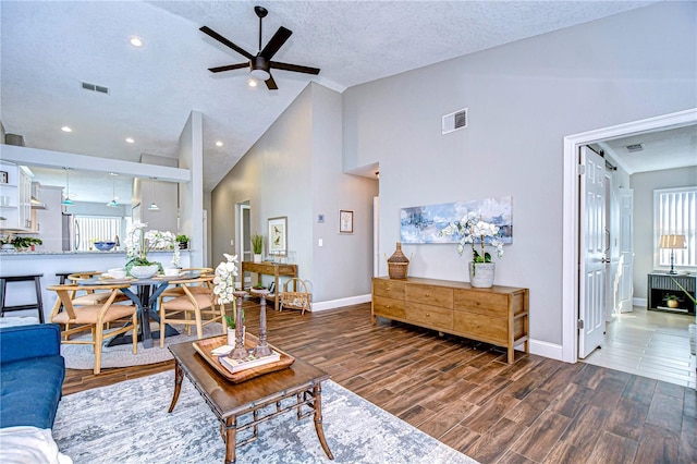 living room featuring ceiling fan, dark wood-type flooring, high vaulted ceiling, and a textured ceiling