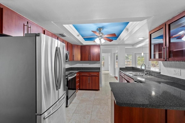 kitchen featuring appliances with stainless steel finishes, sink, ceiling fan, kitchen peninsula, and a raised ceiling