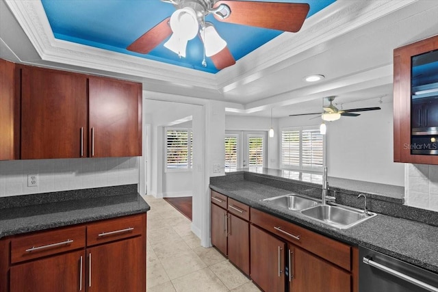 kitchen with sink, decorative backsplash, stainless steel dishwasher, a tray ceiling, and crown molding