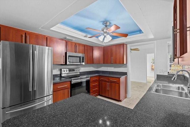 kitchen with a raised ceiling, sink, light tile patterned floors, ceiling fan, and stainless steel appliances