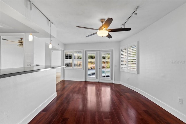 unfurnished living room with ceiling fan, track lighting, dark hardwood / wood-style flooring, and french doors