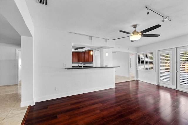 unfurnished living room with hardwood / wood-style floors, rail lighting, sink, and ceiling fan