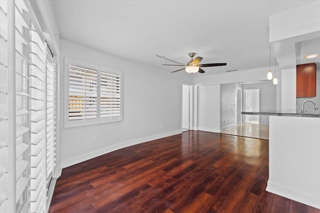 unfurnished living room featuring ceiling fan, dark hardwood / wood-style floors, and sink