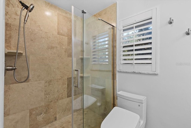 bathroom featuring toilet and a shower with shower door