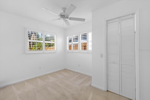 unfurnished bedroom featuring ceiling fan, light colored carpet, and a closet