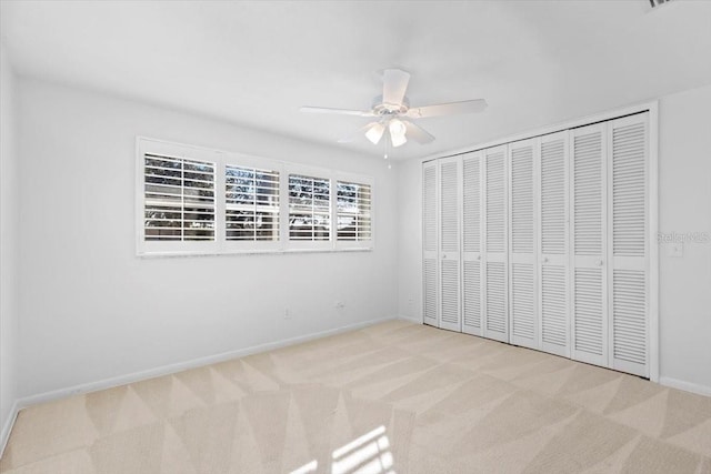 unfurnished bedroom with light carpet, ceiling fan, and a closet