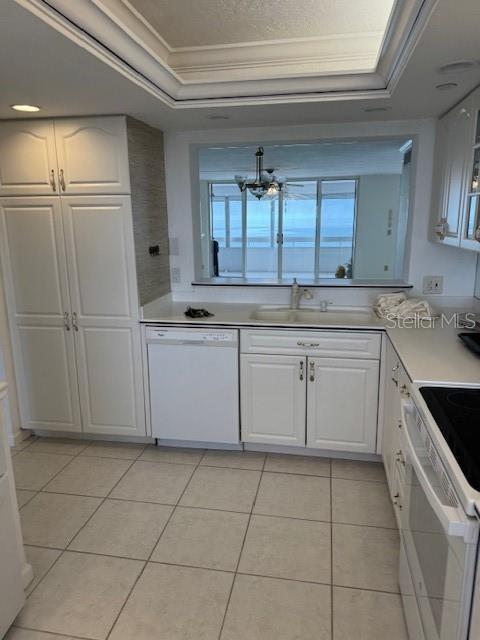 kitchen with crown molding, white appliances, a tray ceiling, and white cabinets