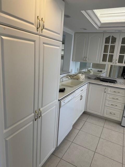 kitchen featuring dishwasher, sink, light tile patterned flooring, and white cabinets