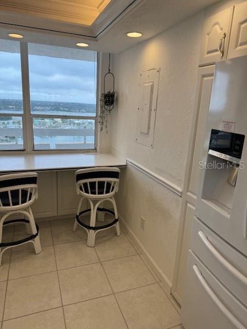 kitchen featuring light tile patterned flooring, ornamental molding, electric panel, and stainless steel fridge with ice dispenser