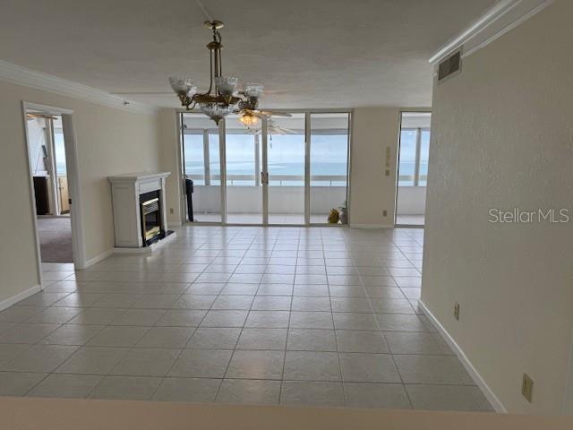 interior space featuring light tile patterned floors, ornamental molding, expansive windows, and a chandelier