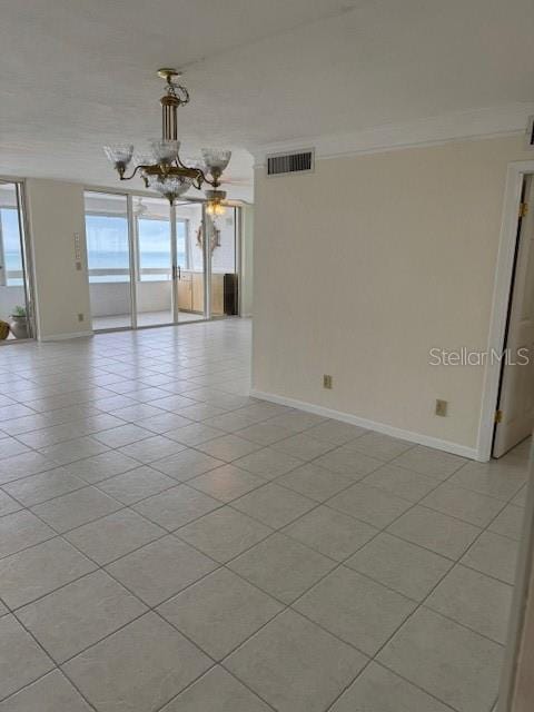 tiled empty room with crown molding and a chandelier