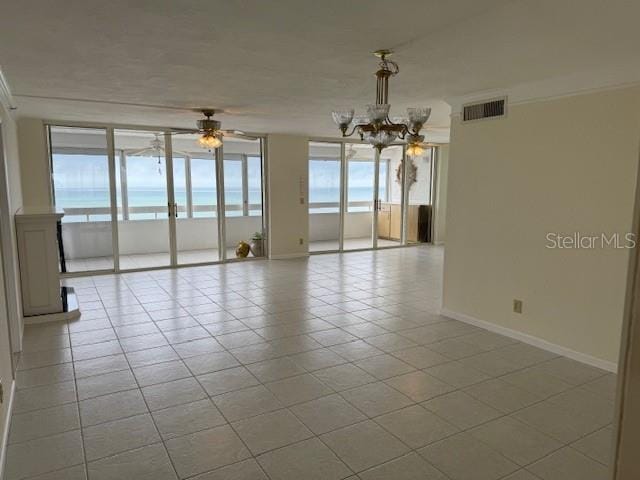 spare room with a wall of windows, ceiling fan with notable chandelier, and light tile patterned floors