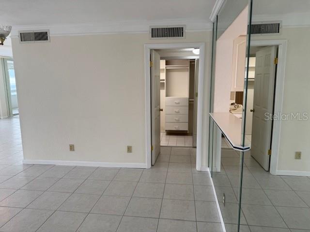 unfurnished bedroom featuring ornamental molding, a spacious closet, light tile patterned flooring, and a closet