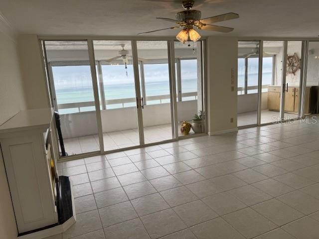 interior space featuring a water view, ceiling fan, and light tile patterned floors