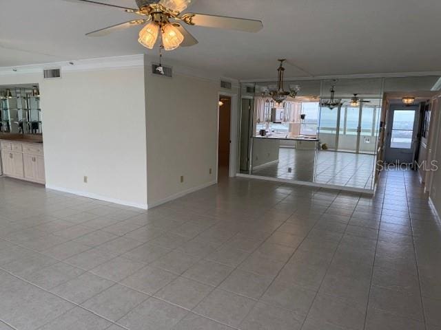 empty room featuring crown molding, ceiling fan with notable chandelier, and tile patterned floors