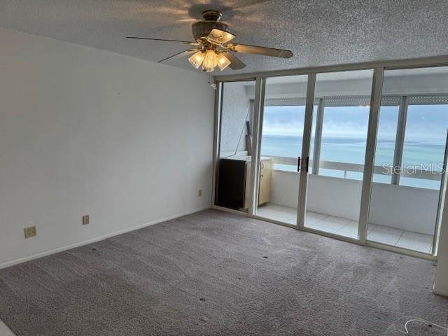 carpeted empty room with ceiling fan and a textured ceiling