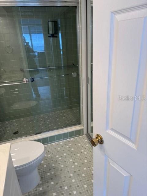 bathroom with vanity, a shower with shower door, tile patterned floors, and toilet