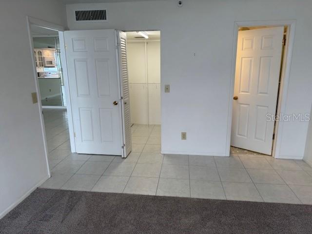 unfurnished bedroom featuring a spacious closet, light tile patterned floors, and a closet