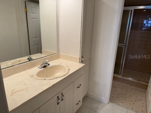 bathroom featuring a shower with door, vanity, and tile patterned floors