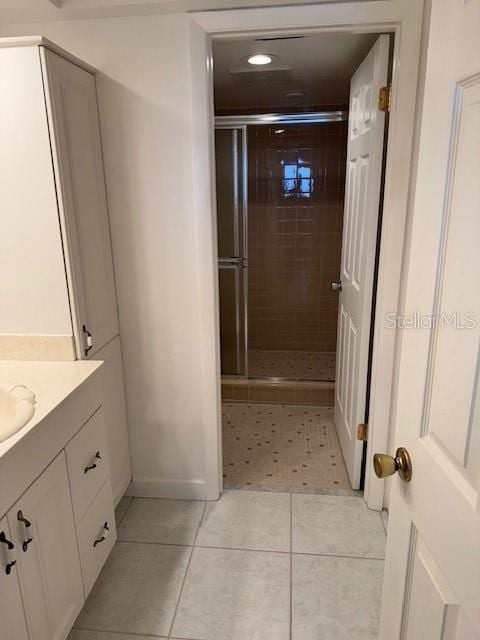 bathroom featuring tile patterned floors, vanity, and a shower with shower door