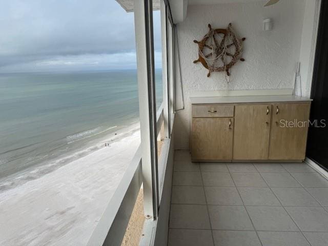 balcony with a water view and a view of the beach