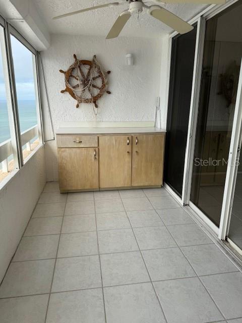 unfurnished sunroom with ceiling fan and a water view