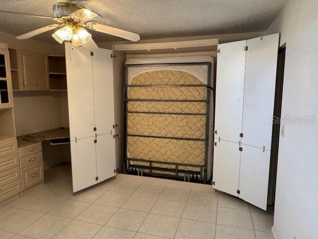 unfurnished bedroom with ceiling fan, light tile patterned floors, and a textured ceiling