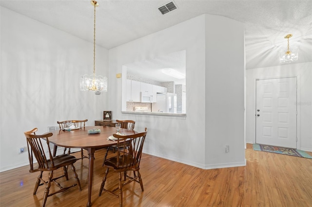 dining room featuring an inviting chandelier, light hardwood / wood-style flooring, and a textured ceiling