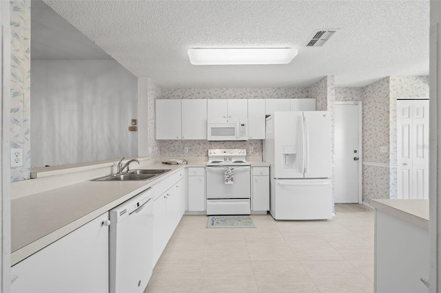 kitchen with sink, white appliances, light tile patterned floors, white cabinetry, and a textured ceiling