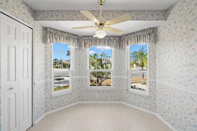 interior space featuring tile patterned flooring, ceiling fan, and a textured ceiling