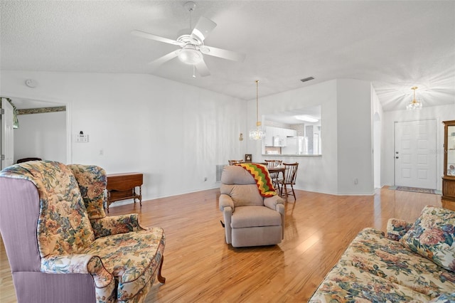 living room featuring lofted ceiling, a textured ceiling, light hardwood / wood-style flooring, and ceiling fan