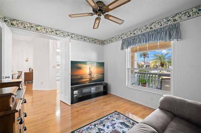 living room featuring ceiling fan, wood-type flooring, and a textured ceiling