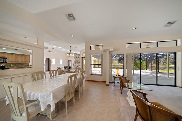 tiled dining area featuring vaulted ceiling and ceiling fan with notable chandelier