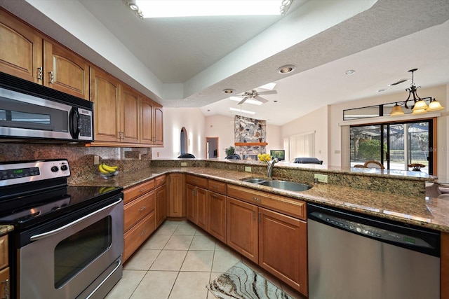 kitchen featuring sink, light tile patterned floors, appliances with stainless steel finishes, vaulted ceiling, and dark stone counters