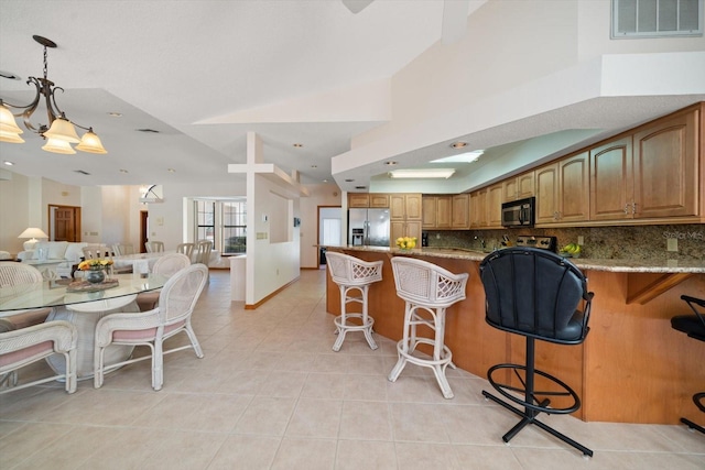 kitchen featuring light tile patterned flooring, decorative light fixtures, tasteful backsplash, stainless steel fridge, and light stone countertops