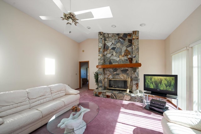 living room with a stone fireplace, lofted ceiling with skylight, ceiling fan, and carpet flooring