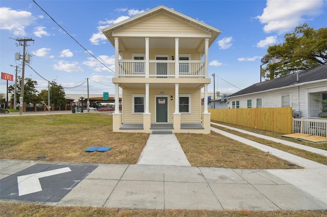 view of front facade with a porch, a balcony, and a front yard