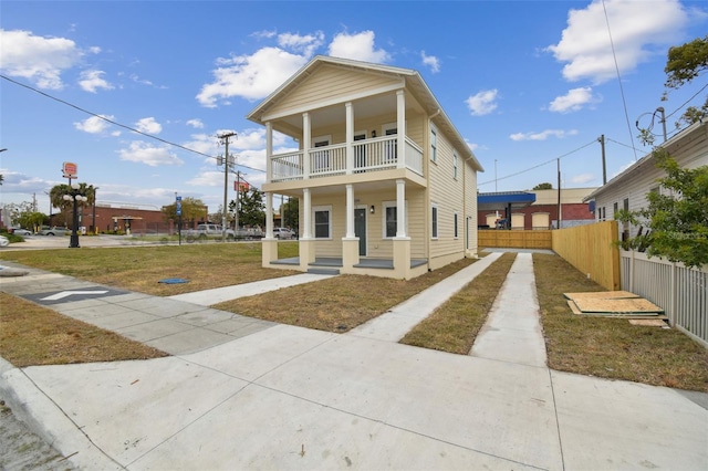 view of front facade featuring a balcony, covered porch, and a front lawn