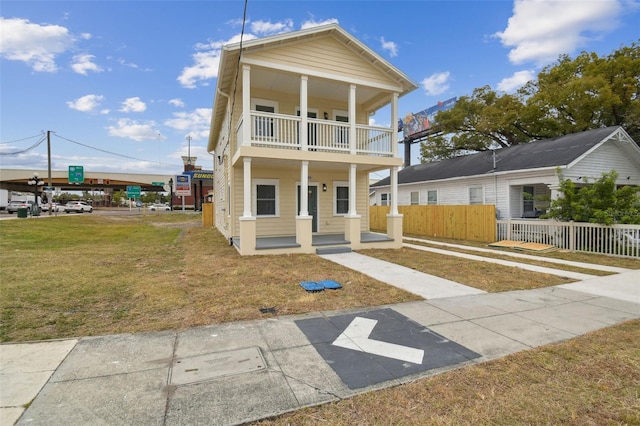 view of front of house featuring a porch, a balcony, and a front lawn