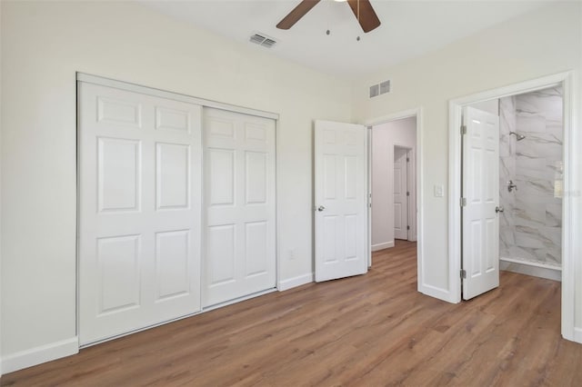 unfurnished bedroom featuring ceiling fan, ensuite bath, light hardwood / wood-style floors, and a closet