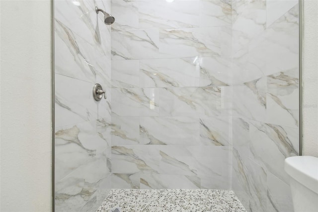 bathroom featuring a tile shower and toilet