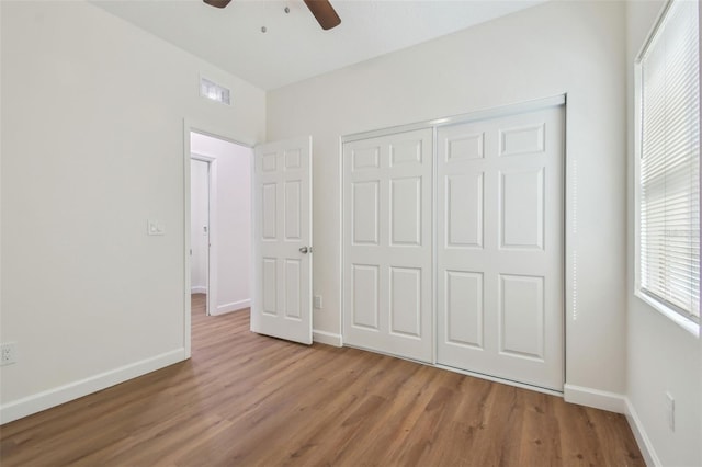 unfurnished bedroom featuring ceiling fan, a closet, and light wood-type flooring