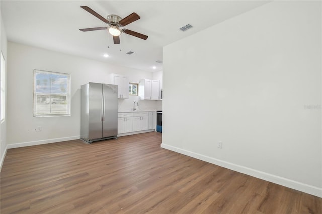 unfurnished living room featuring ceiling fan, sink, and dark hardwood / wood-style flooring