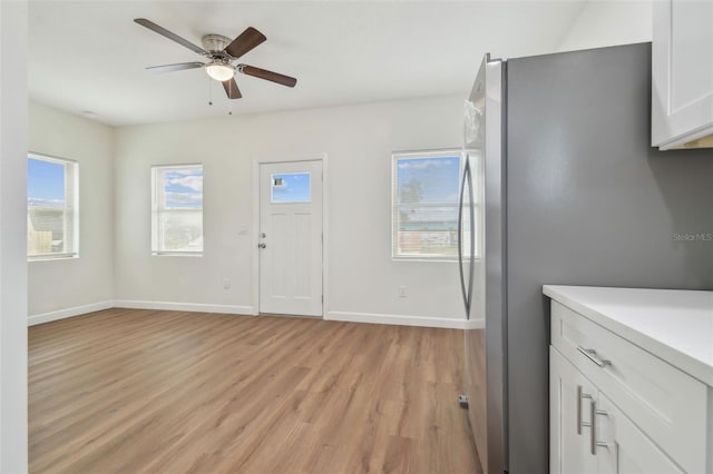 kitchen with white cabinetry, ceiling fan, stainless steel refrigerator, and light hardwood / wood-style floors