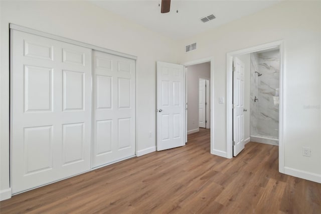 unfurnished bedroom featuring ensuite bath, wood-type flooring, a closet, and ceiling fan