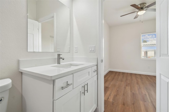 bathroom featuring wood-type flooring, vanity, ceiling fan, and toilet