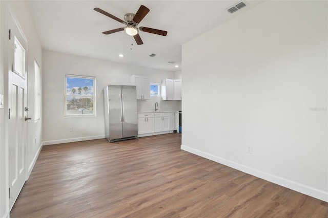 unfurnished living room with sink, hardwood / wood-style floors, and ceiling fan