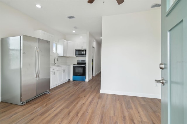 kitchen featuring white cabinetry, sink, light wood-type flooring, and appliances with stainless steel finishes