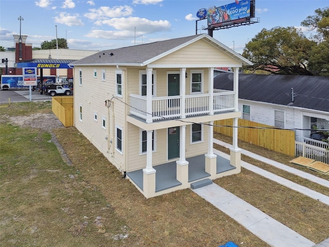 view of front facade with a balcony, covered porch, and a front lawn