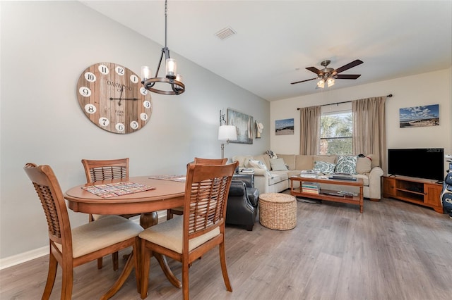 dining space featuring hardwood / wood-style flooring and ceiling fan with notable chandelier